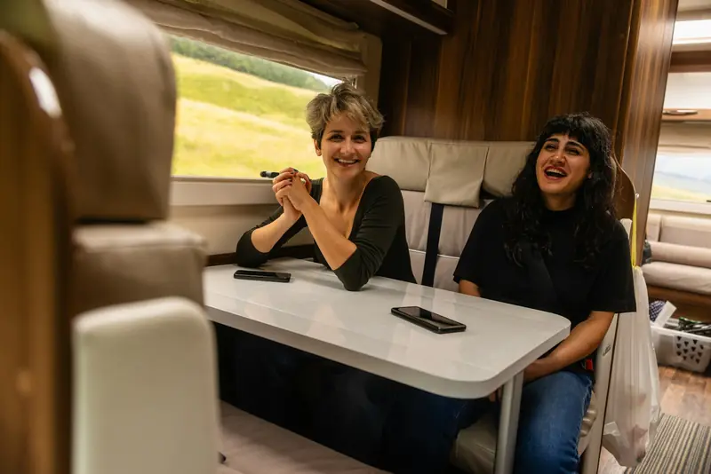 Two travellers at the dinette table inside a motorhome